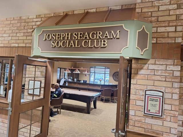 Open wooden doors under a sign reading Joseph Seagram Social Club, with a pool table, chairs and a seated man inside.