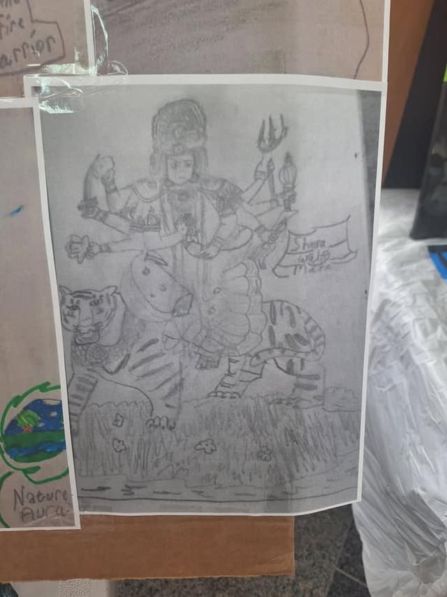 Pencil drawing of a multi-armed figure riding a tiger, taped to a display board, with the words "Nature Aura" on a nearby piece.