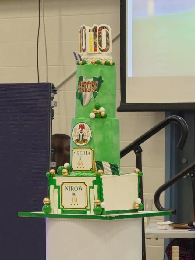 A tiered green and white cake topped with a 10, with labels reading "NIGERIA @ 66" and "NIROW @ 10" and a Nigerian flag design.