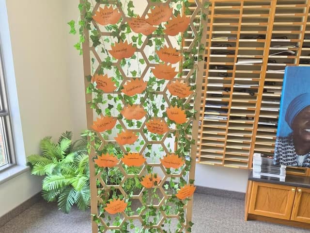 A hexagon lattice with ivy and orange paper flowers bearing handwritten words like Respect, Prayer and Friendliness.