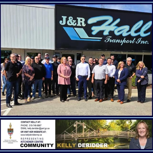 A large group of people in business and casual clothes pose outdoors in front of a building with a J&R Hall Transport Inc. sign.