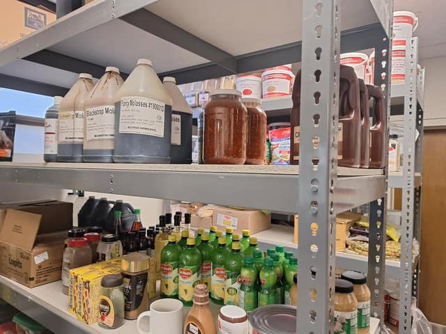 Pantry shelves hold jugs of molasses, jars of sauce, bottles of lemon juice, spices and boxed goods.