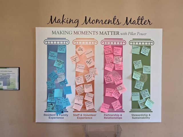 A wall display titled Making Moments Matter with Pillar Power shows four colored pillars covered in sticky notes from staff and volunteers.