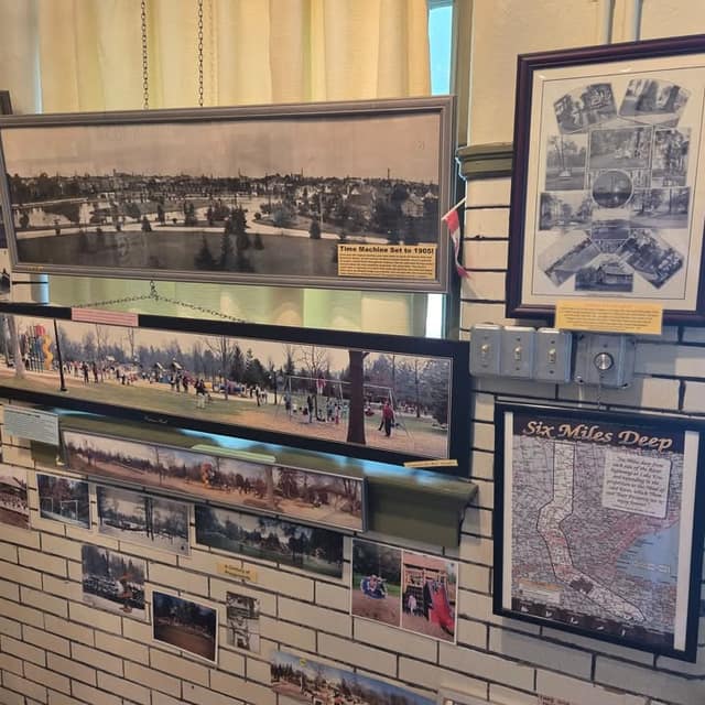 Gallery wall of panoramic historic and modern park photos, a framed collage of old views, and a map titled Six Miles Deep.