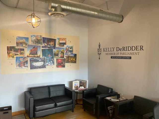 Waiting area with black leather sofa and chairs beneath the postcard mural, beside a wall sign reading Kelly DeRidder, Member of Parliament, Kitchener Centre.
